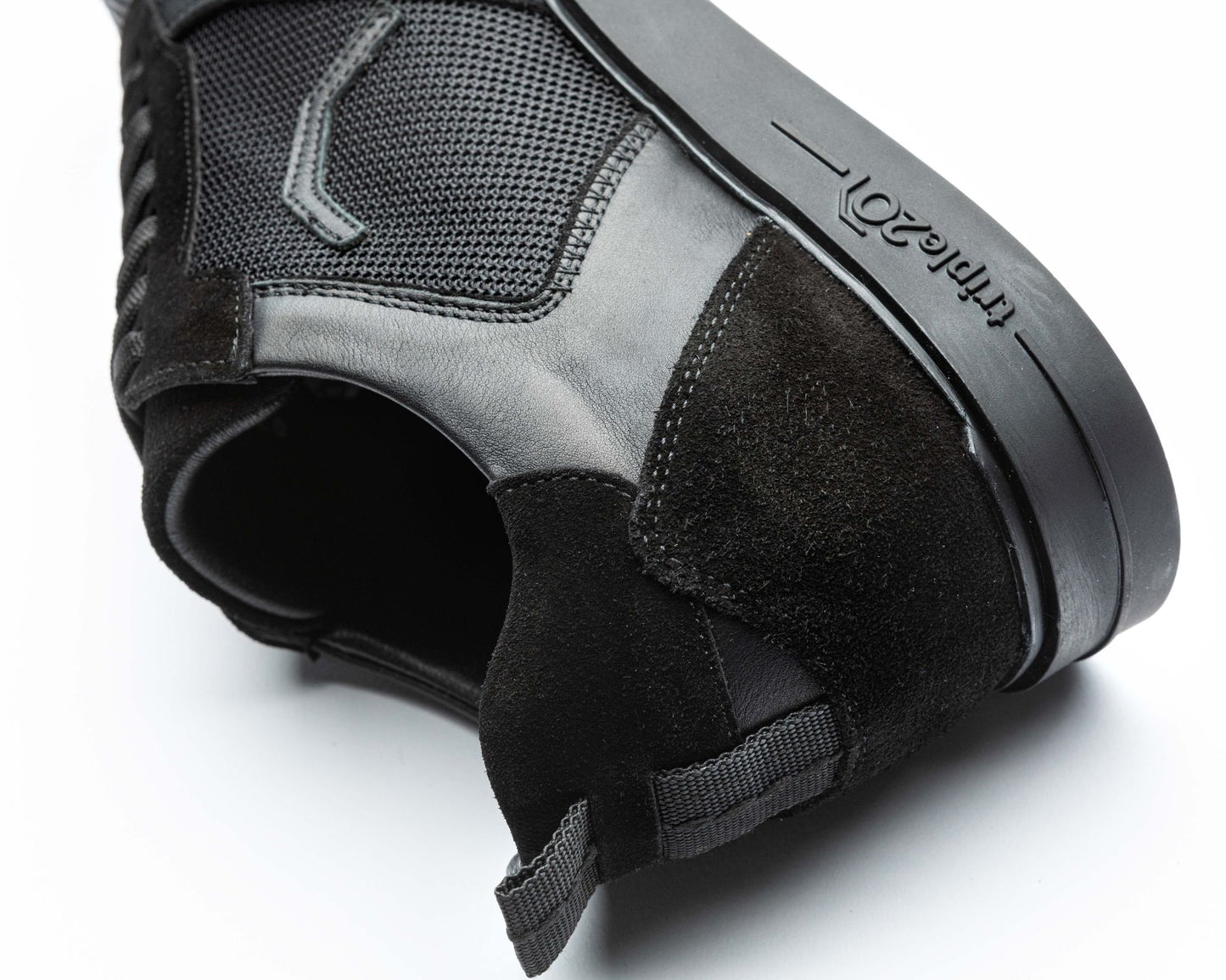 Nahaufnahme eines schwarzen triple20 Dartsschuhs, zu sehen ist der Schuh in auf der Seite liegender Position mit Fokus auf die Hinterkappe. Erkennbar, neben den zahlreichen Details, ist zum Beispiel das feine schwarze Lederfutter des Modells.