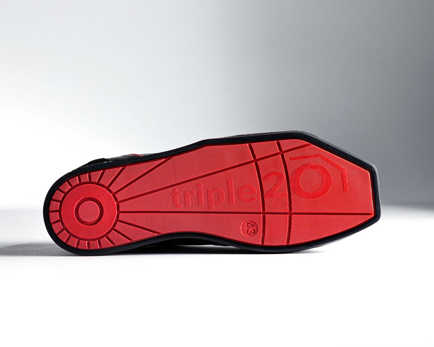 Ansicht einer leuchtend roten Laufsohle eines triple20 Dartschuhs. Durch den schwarzen Rahmen wird die Speziallaufsohle exakt umrissen, sodass die Winkelform deutlich zur Geltung kommt. Auch fällt auf, mit wieviel Liebe zum Detail die Unterseite der Sohle designt wurde. Wem ein ausschließlich schwarzer Schuh zu langweilig ist, wird dieses Modell lieben.