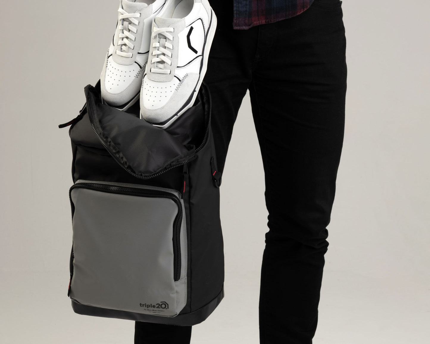 Produktfoto eines speziell für den Dartsport entworfenen Rucksacks. Auf diesem Bild wird gezeigt, wie leicht ein Paar der triple20 Dartschuhe, die eine Weltneuheit darstellen, im Rucksack verstaut werden kann. Die Schuhe sind aus Vollleder und weiß, der Rucksack ist schwarz-grau mit roten Akzenten.